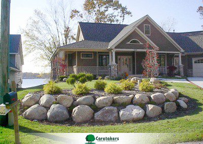 A beautiful home with rock retaining wall and green grass captures what Landscaping maintenance West Michigan is all about.